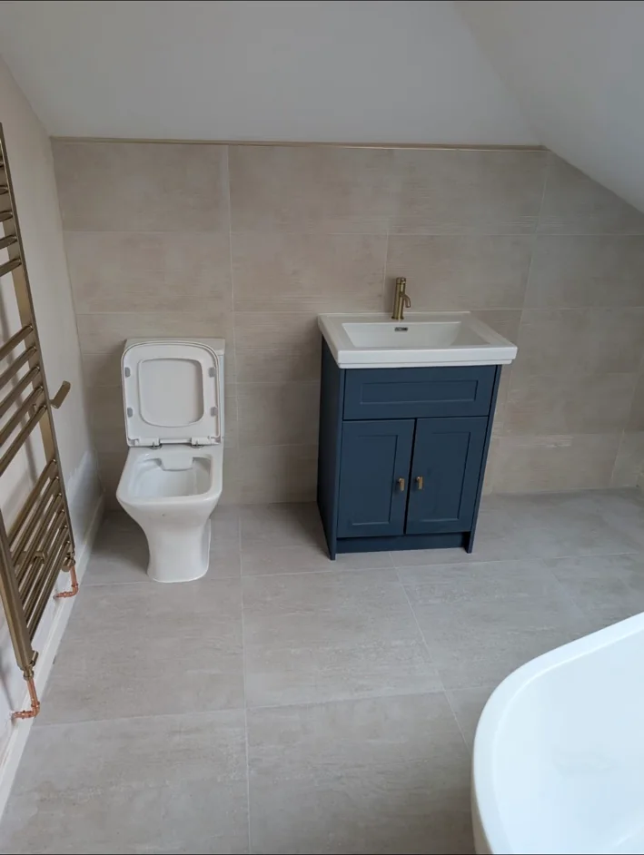 Finished bathroom with navy vanity unit and brushed brass tap